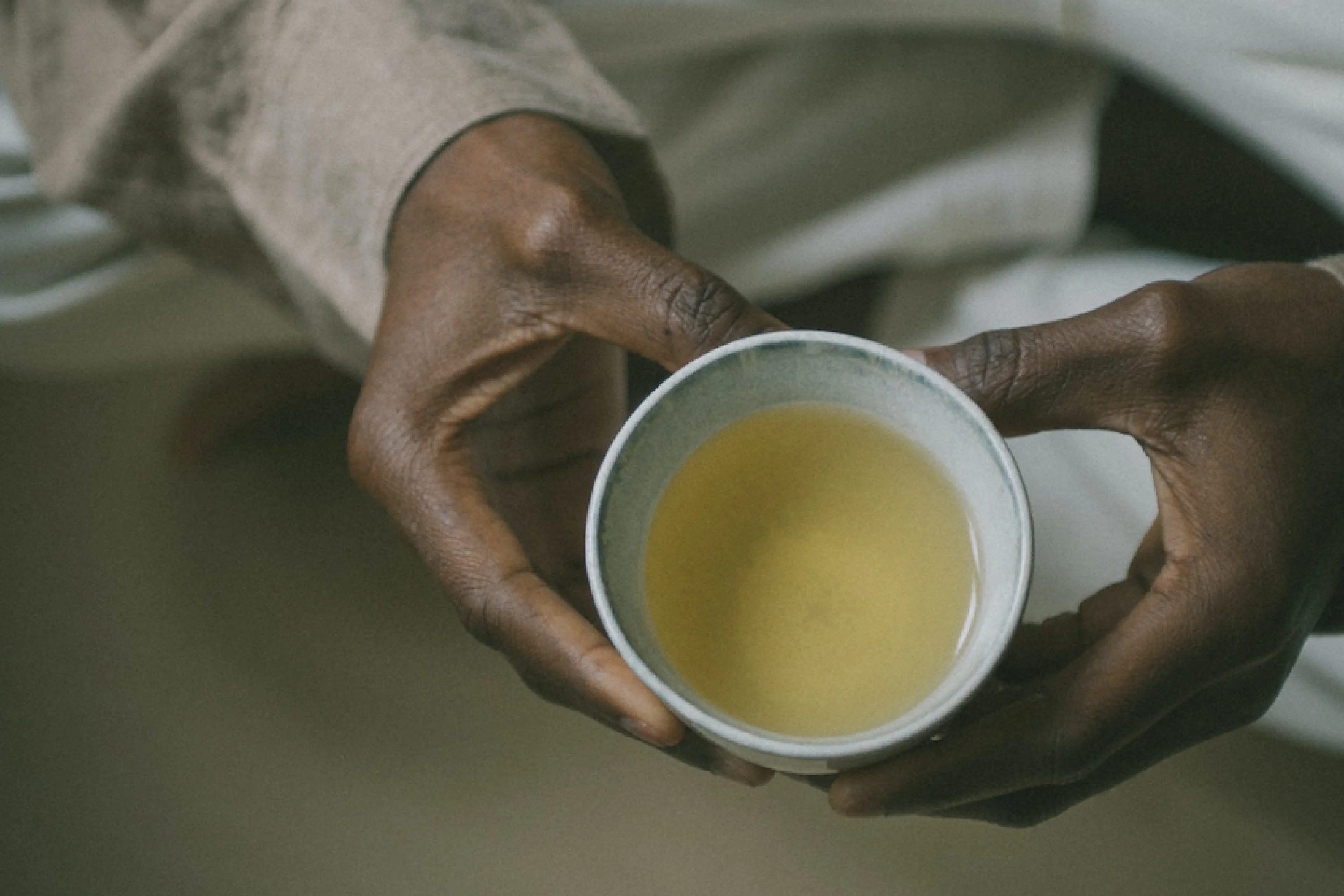 hands holding a white cup of tea